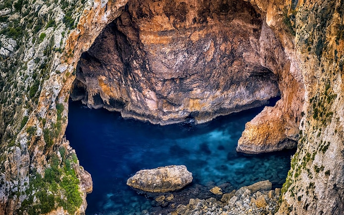 Blue Grotto sea cave with clear blue water and rocky cliffs in Malta.