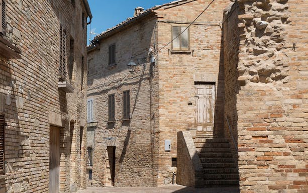 Stone buildings and narrow alley in an Italian village, part of a Free Vespa Tour.