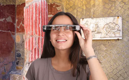 Person using augmented reality glasses at Herculaneum ruins with ancient frescoes.
