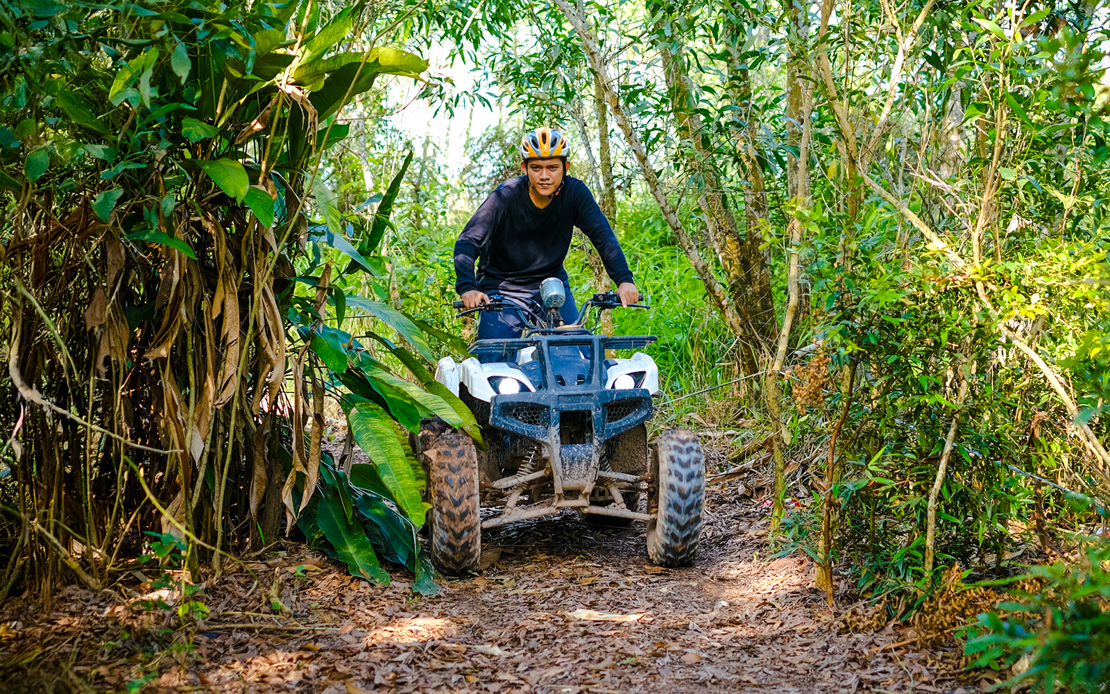 Man riding an ATV through forest trail at Batam Adventure Park.