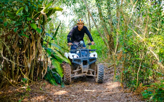 Man riding an ATV through forest trail at Batam Adventure Park.
