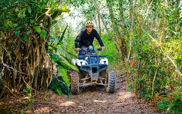 Man riding an ATV through forest trail at Batam Adventure Park.