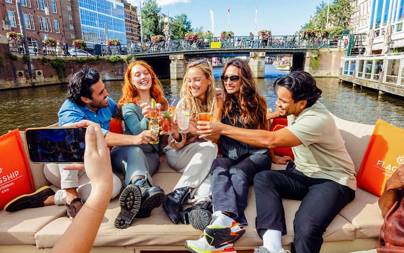 Tourists enjoying drinks on a canal cruise in Amsterdam.
