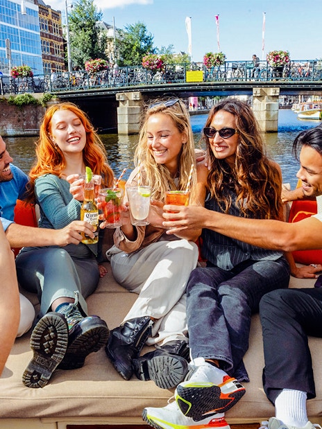 Tourists enjoying drinks on a canal cruise in Amsterdam.