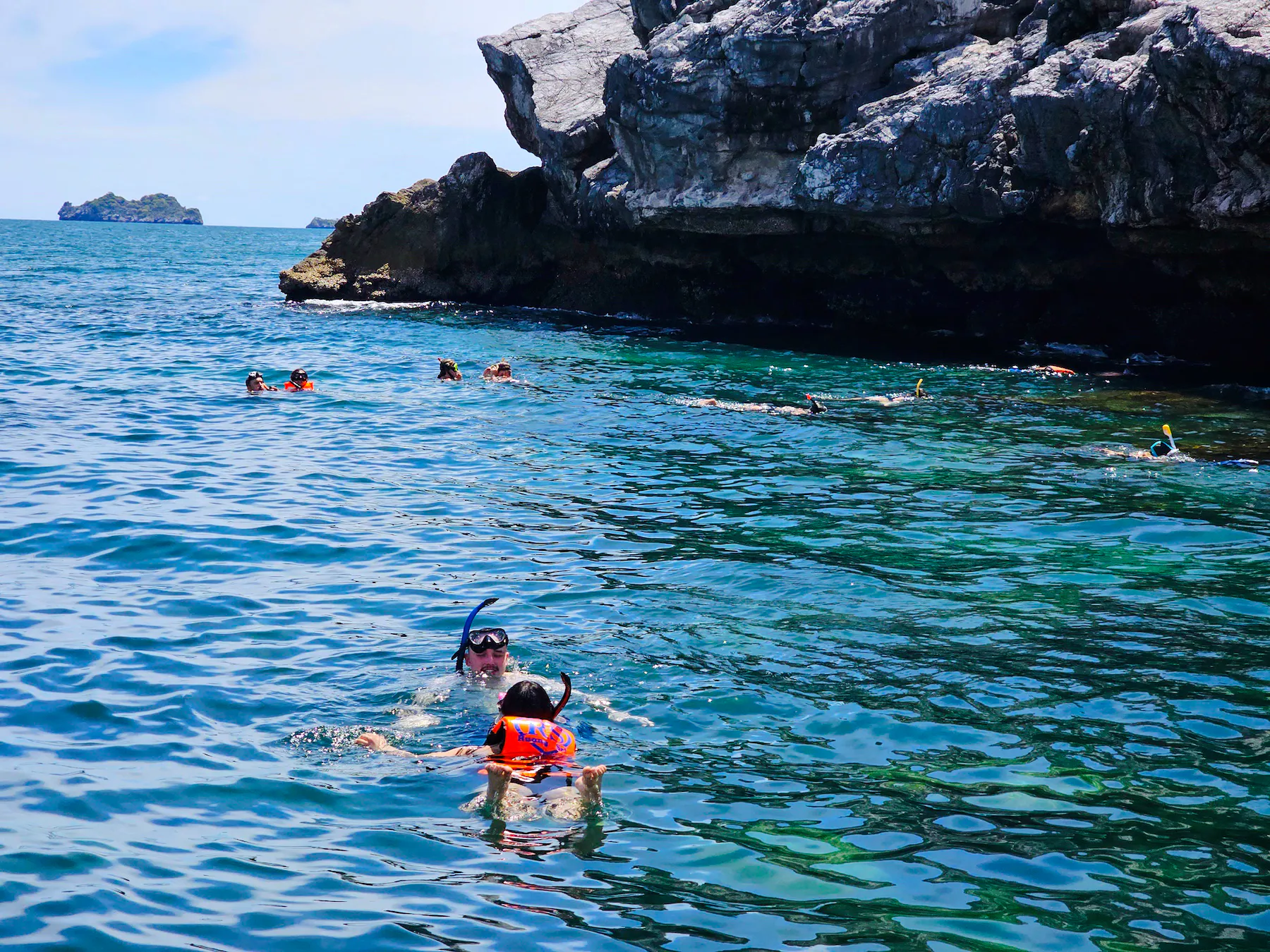 Snorkelers exploring clear waters near rocky cliffs on Ang Thong day tour, Koh Samui.