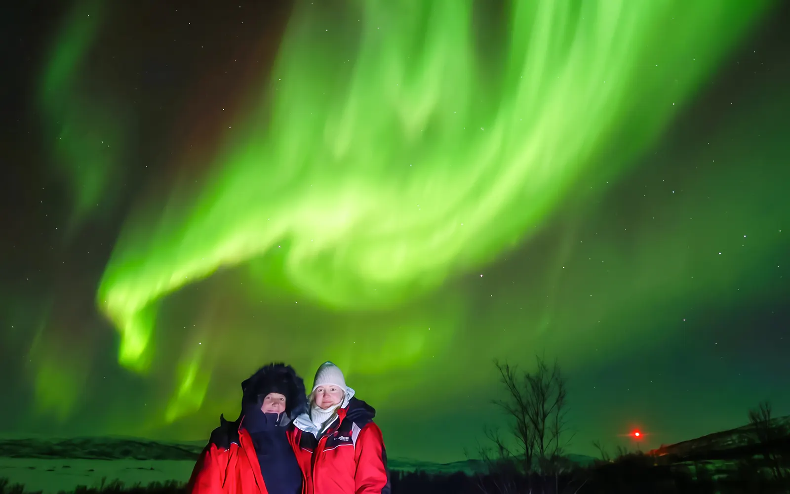 Couple viewing Northern Lights in Abisko, Sweden during a guided tour.