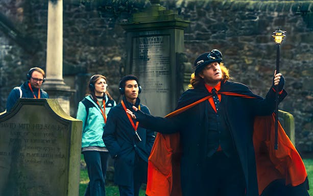 Guide holding a lamp and leading a ghost tour in Edinburgh