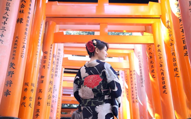 Person in kimono walking through torii gates at Fushimi Inari Shrine, Kyoto, Japan.