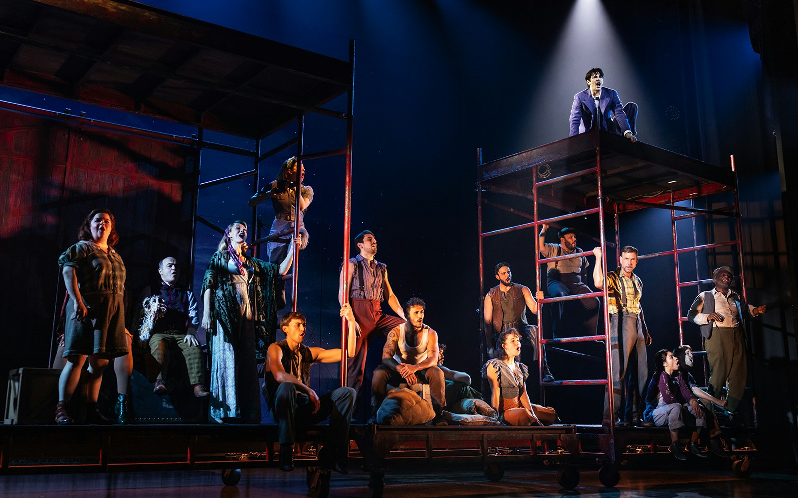 Stage performance of "Water for Elephants" with actors on scaffolding under spotlight.