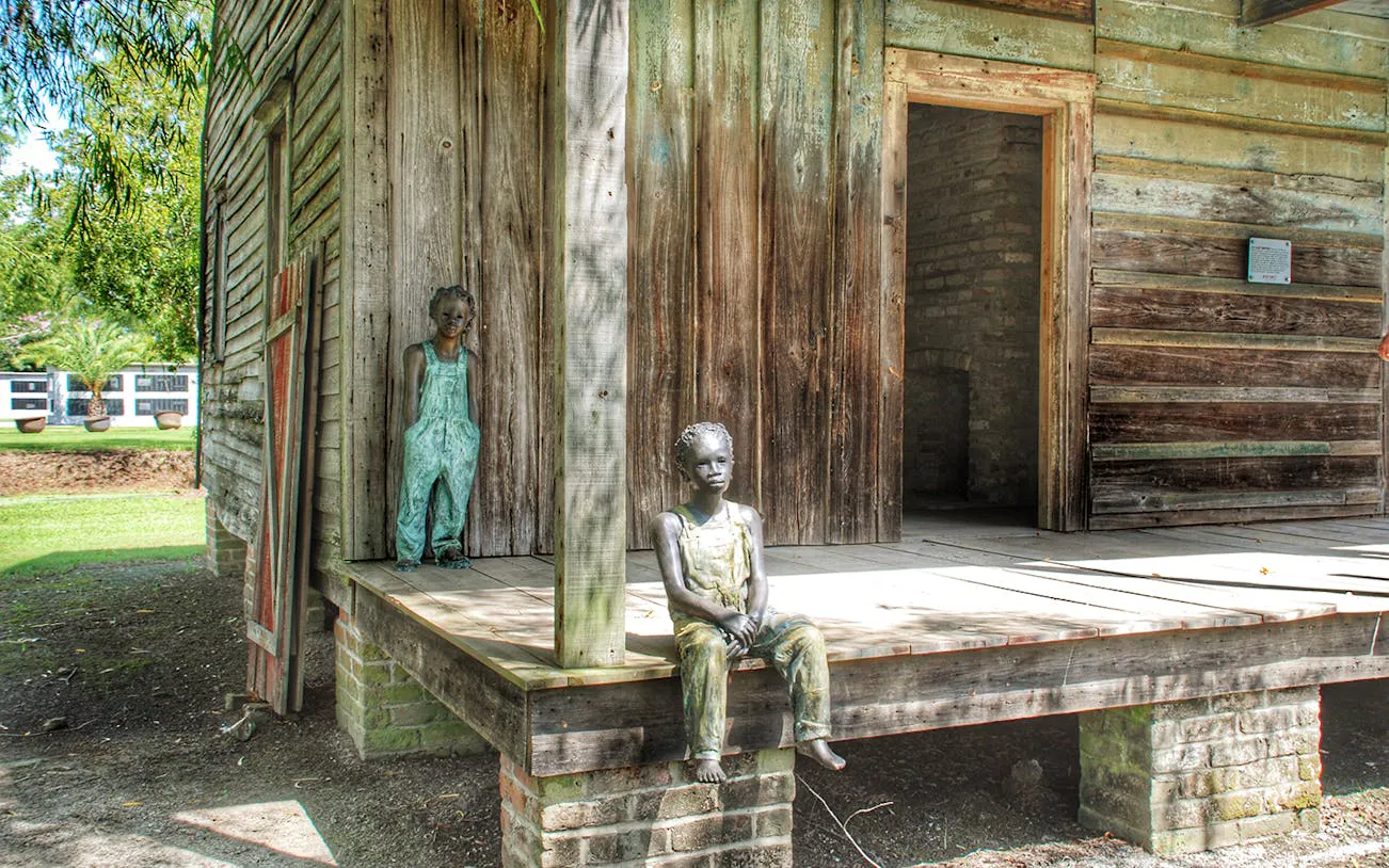 Statues of children on a wooden porch at Whitney Plantation, New Orleans.