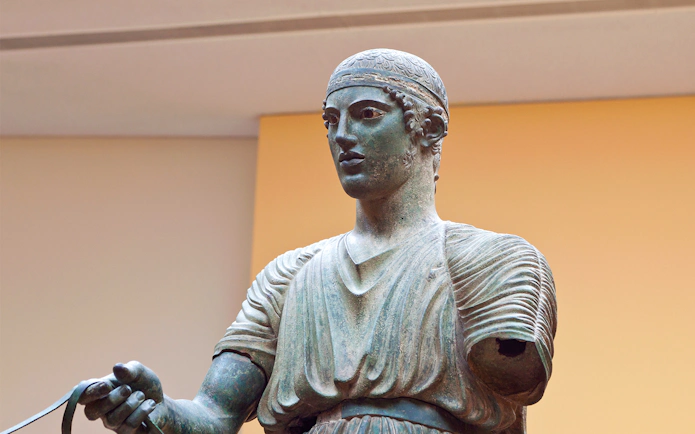 Charioteer statue at Delphi Museum, Greece, holding reins.