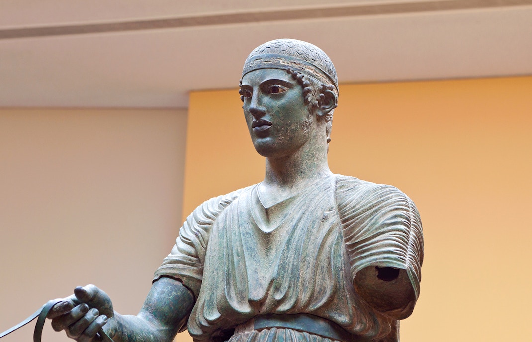 Charioteer statue at Delphi Museum, Greece, holding reins.