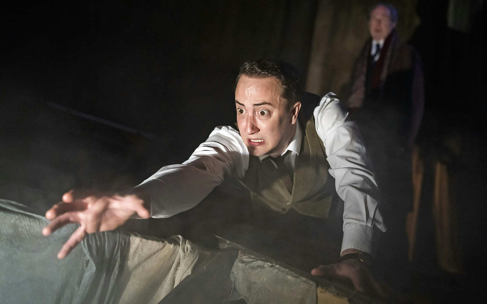 Man reaching out in a dramatic scene from "The Woman in Black" play.