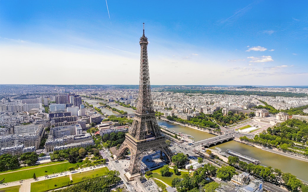 Aerial view of the Eiffel Tower in Paris with the Seine River and cityscape.