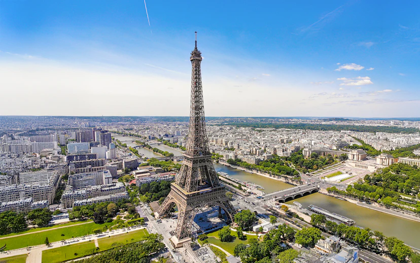 Aerial view of the Eiffel Tower in Paris with the Seine River and cityscape.