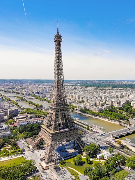 Aerial view of the Eiffel Tower in Paris with the Seine River and cityscape.