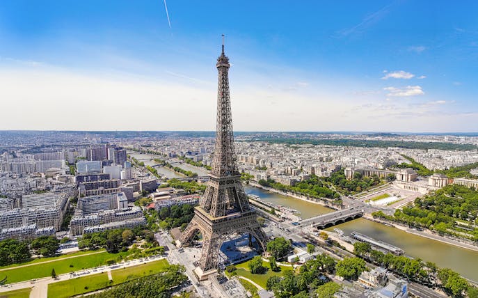 Aerial view of the Eiffel Tower in Paris with the Seine River and cityscape.