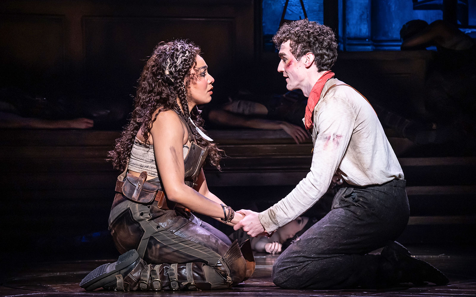 Two actors performing a scene in Hadestown musical, holding hands on stage.