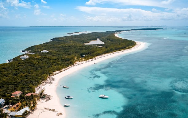 Aerial view of Rose Island's tropical beach with boats in turquoise water.