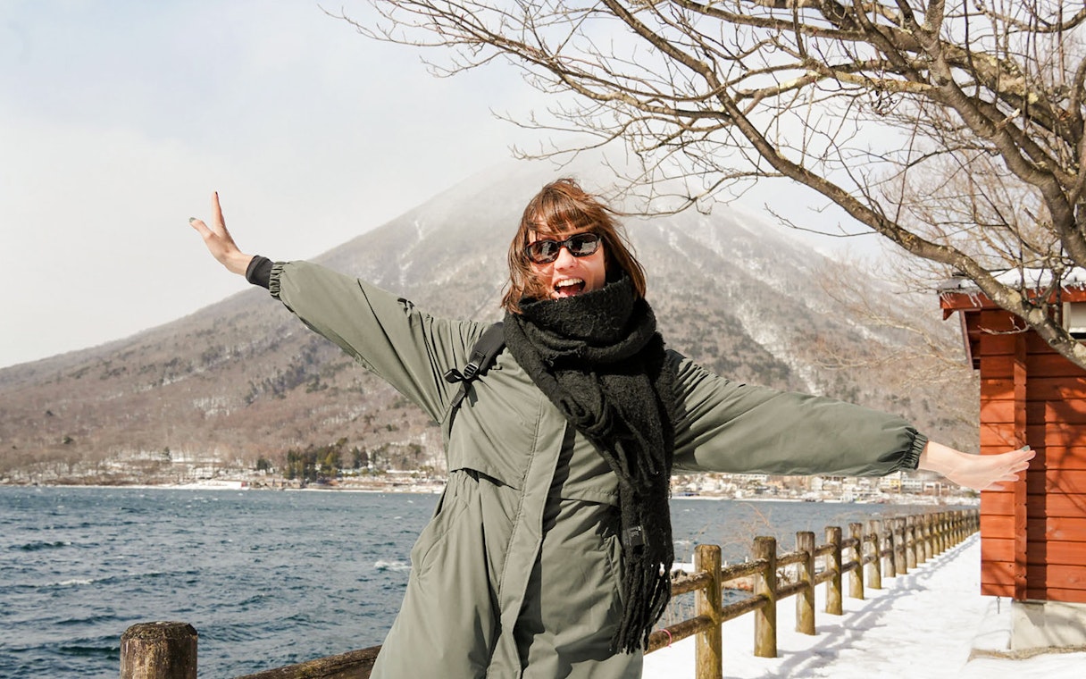 Tourist enjoying winter at Lake Chuzenji with mountains in the background.