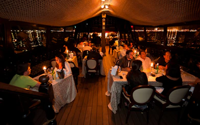 Dinner guests seated on a galleon cruise in Venice, enjoying candlelit tables.