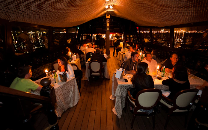 Dinner guests seated on a galleon cruise in Venice, enjoying candlelit tables.