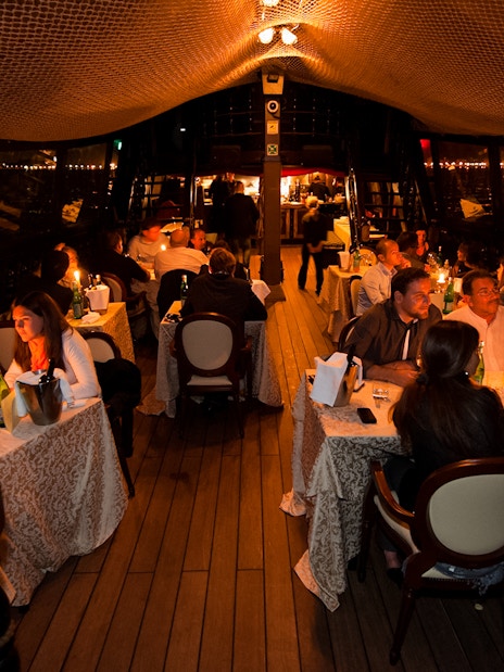 Dinner guests seated on a galleon cruise in Venice, enjoying candlelit tables.