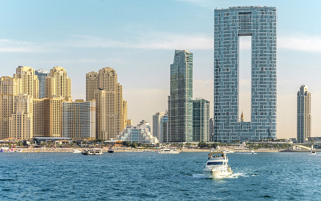 Luxury yacht cruising near Dubai Harbour with city skyline in the background.