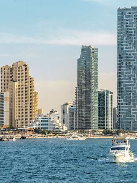 Luxury yacht cruising near Dubai Harbour with city skyline in the background.