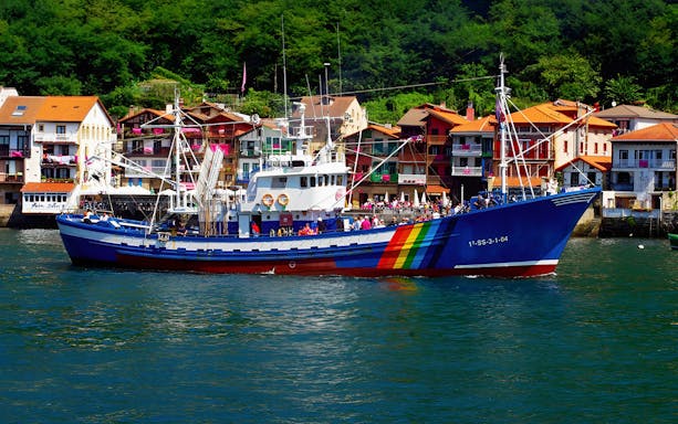 Colorful fishing boat in Hondarribia harbor with vibrant houses in the background.