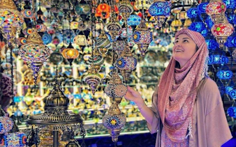 Colorful lanterns in Khan El Khalili market, Cairo, with a visitor admiring the intricate designs.