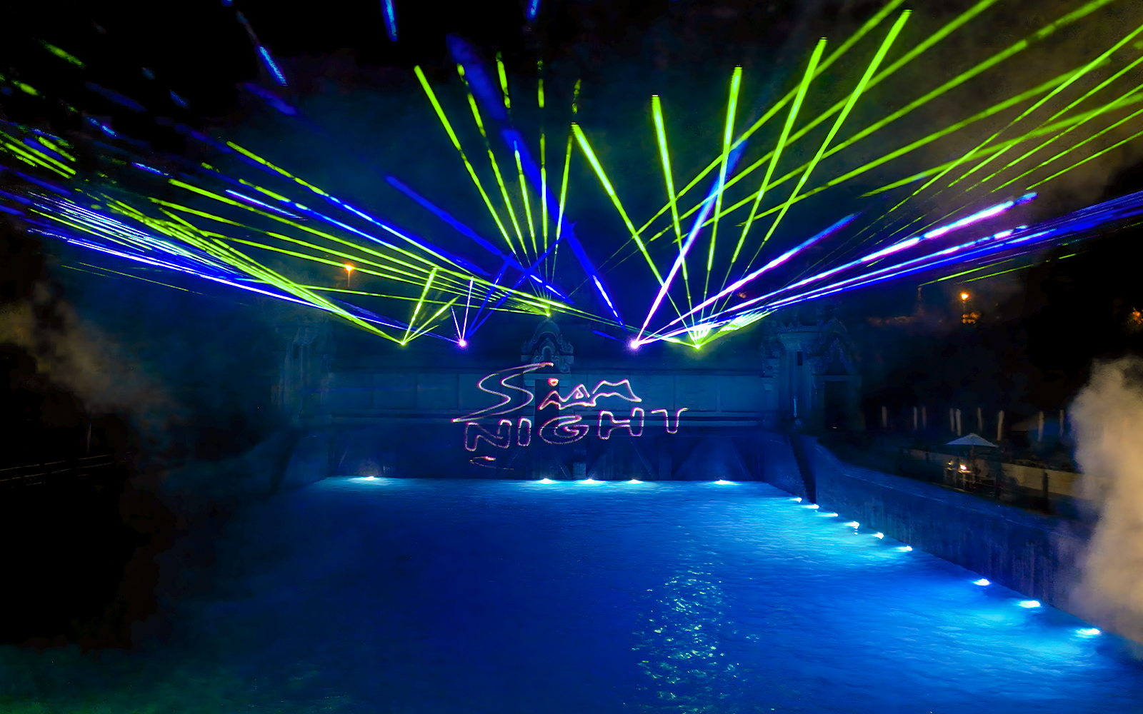 Laser show over water at Siam Park, illuminated at night.