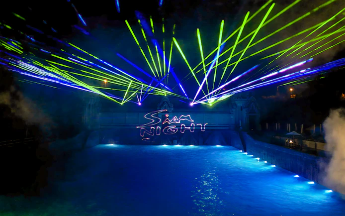 Laser show over water at Siam Park, illuminated at night.