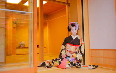 Geisha in traditional kimono posing in a Japanese tea house.