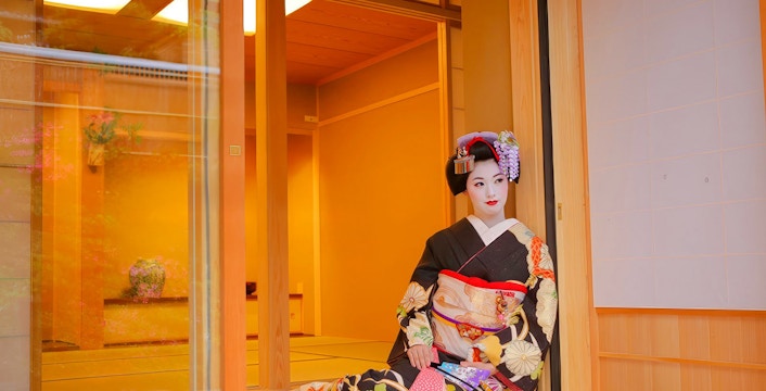 Geisha in traditional kimono posing in a Japanese tea house.