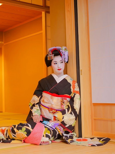 Geisha in traditional kimono posing in a Japanese tea house.