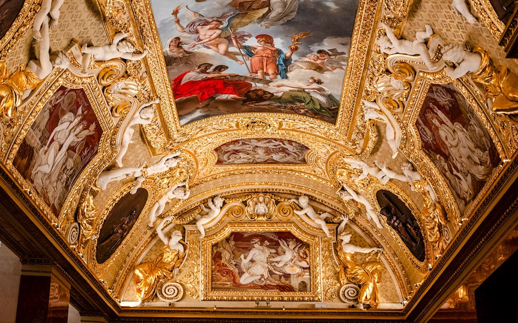 Louvre Museum ornate ceiling with classical paintings and sculptures, Paris, France.