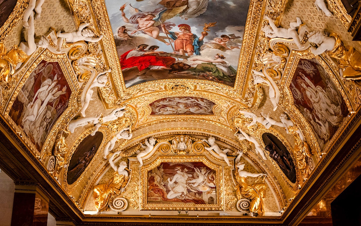 Louvre Museum ornate ceiling with classical paintings and sculptures, Paris, France.