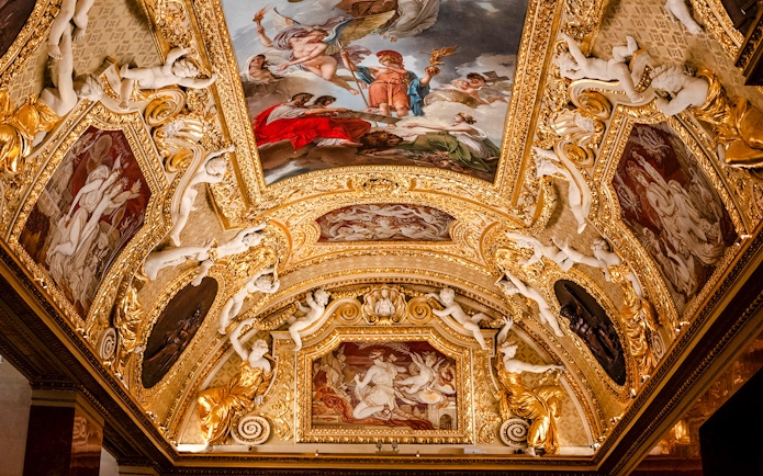 Louvre Museum ornate ceiling with classical paintings and sculptures, Paris, France.