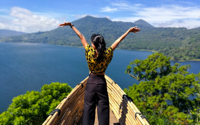 Panoramic view from bamboo boat at Wanagiri Hidden Hills, Bali, overlooking lake and mountains.
