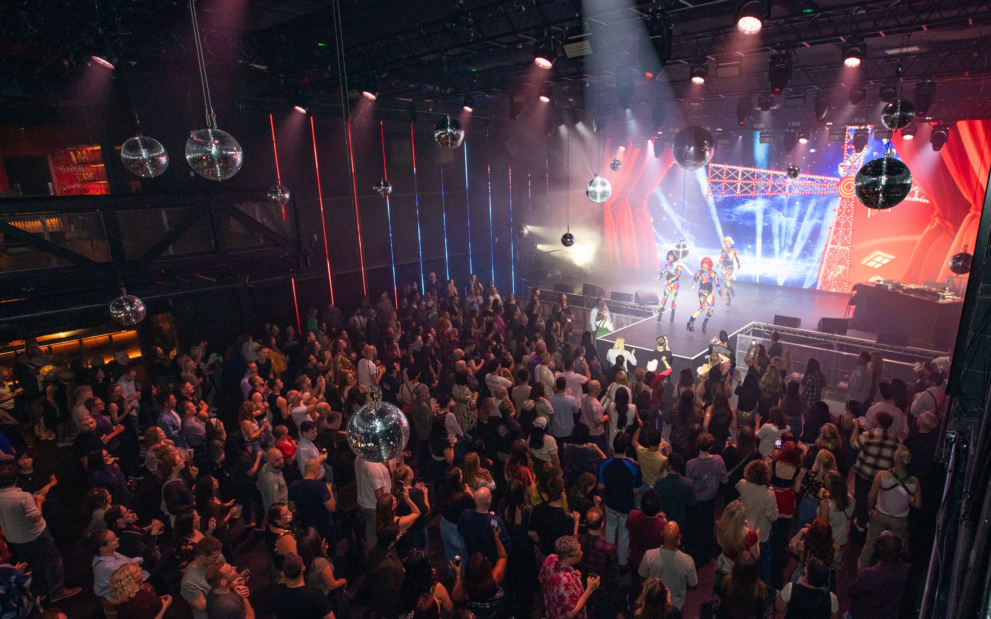 Crowd enjoying a live performance at a West End theater event with vibrant stage lights.