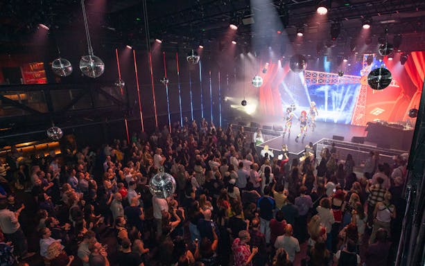 Crowd enjoying a live performance at a West End theater event with vibrant stage lights.