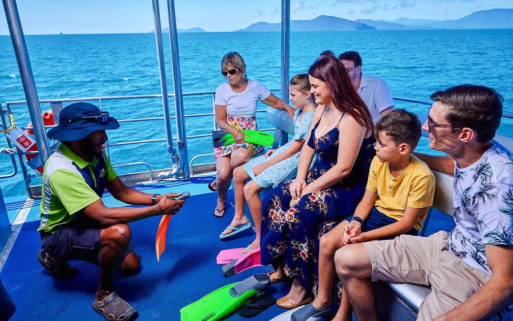 Tour group on a boat near Fitzroy and Green Islands, receiving snorkeling gear briefing.