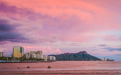 Diamond Head volcano and Honolulu skyline viewed from the ocean at sunset.