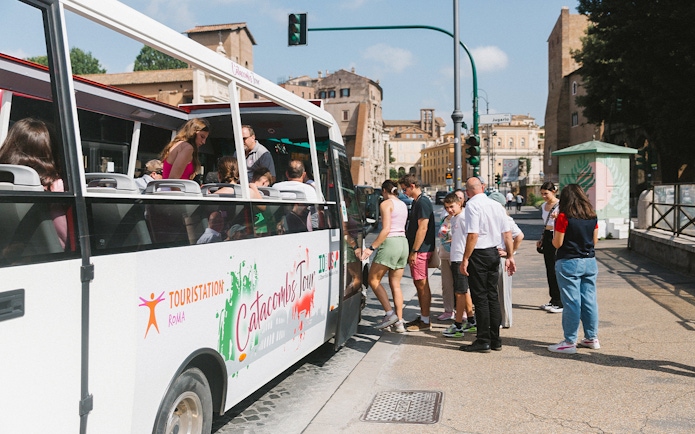 Tourists boarding a bus for a guided tour of the Catacombs in Rome.