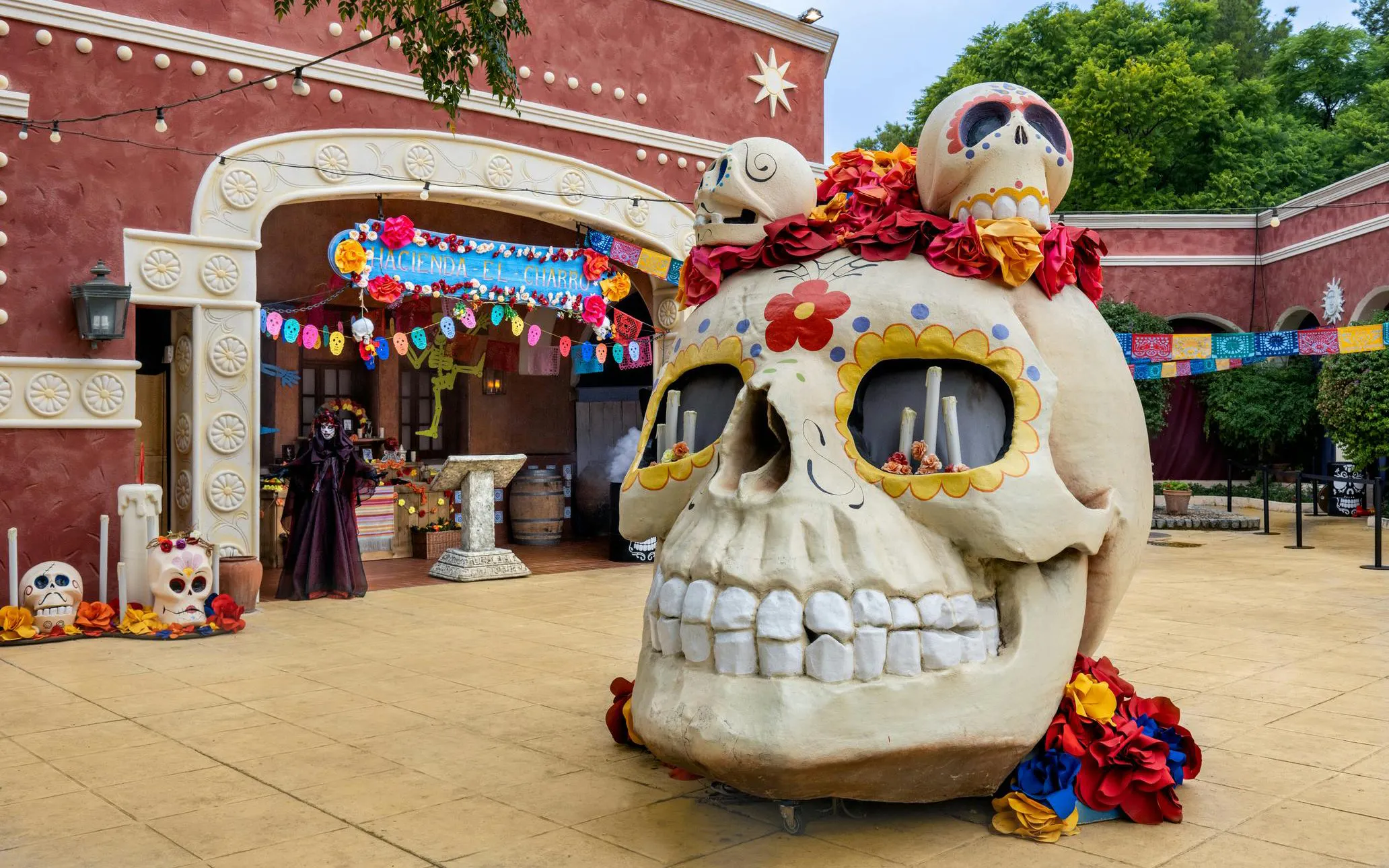 Giant skull decoration at PortAventura Park Halloween event with colorful banners and festive decor.