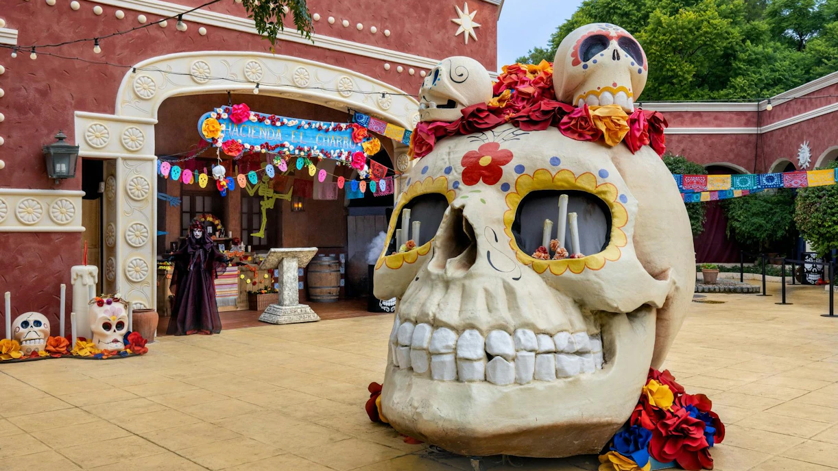Giant skull decoration at PortAventura Park Halloween event with colorful banners and festive decor.