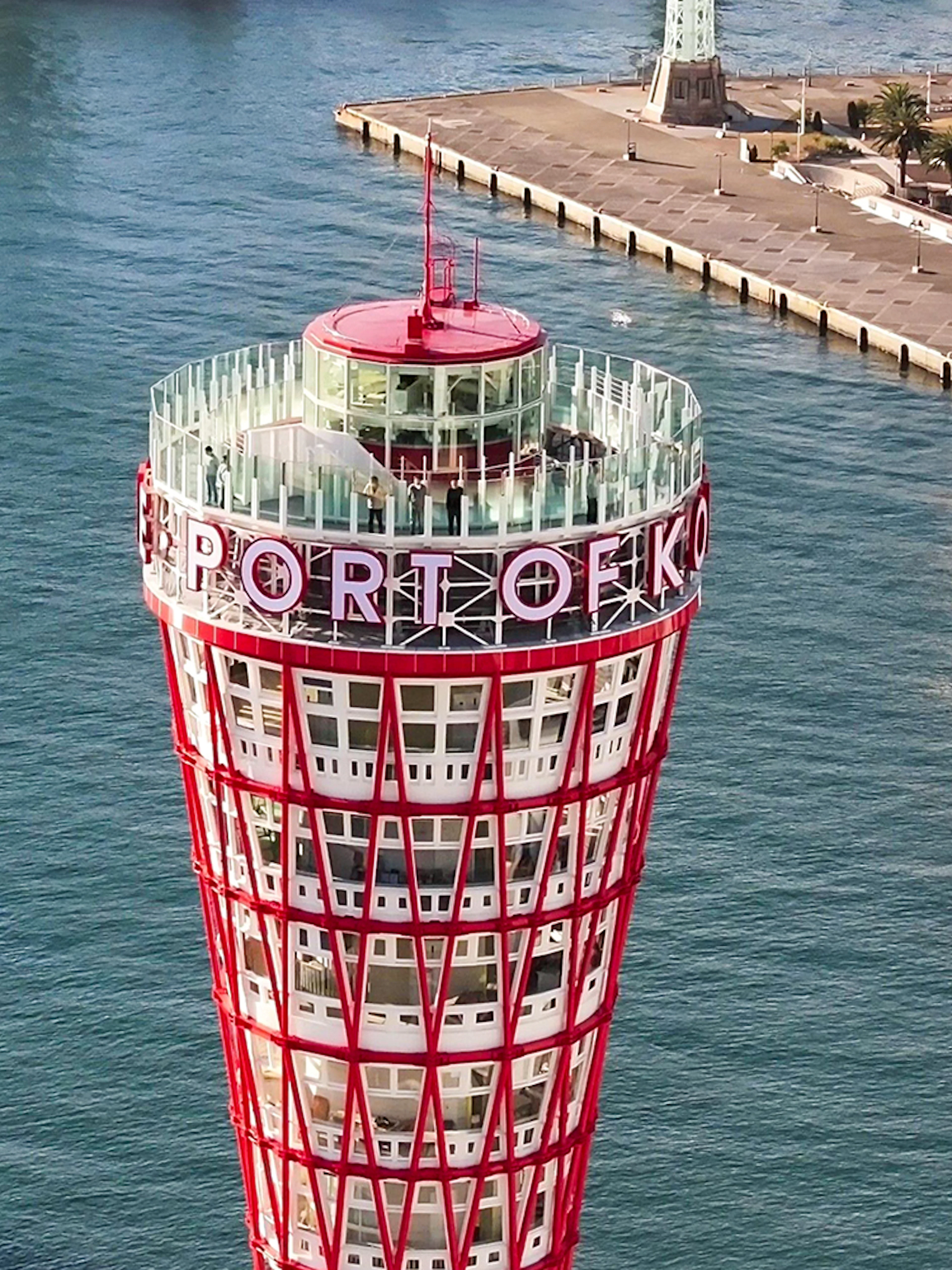 Kobe Port Tower overlooking the harbor with a ferris wheel and docked ship nearby.