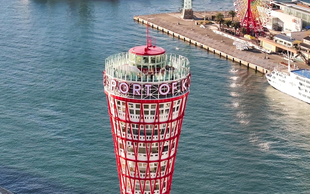 Kobe Port Tower overlooking the harbor with a ferris wheel and docked ship nearby.