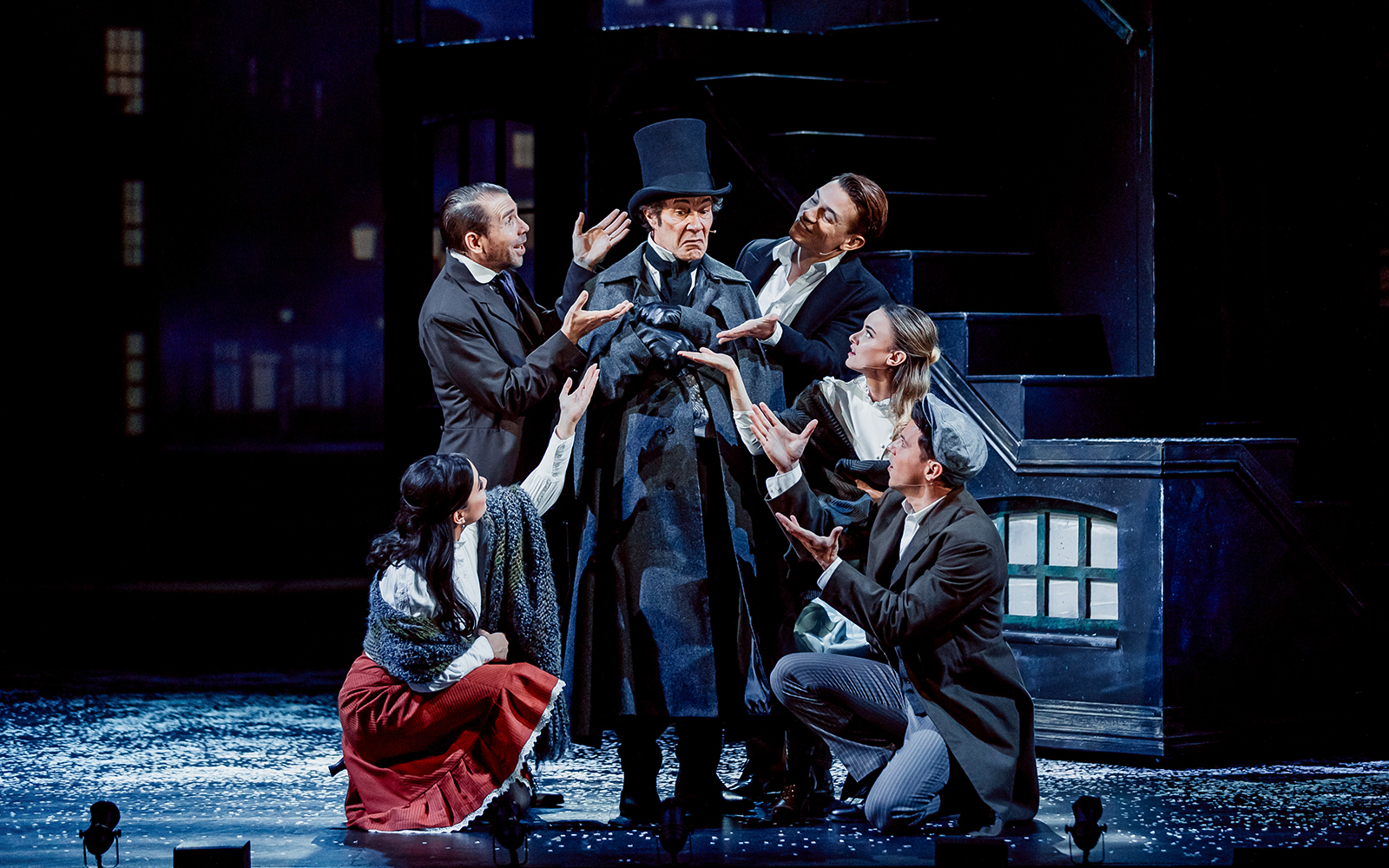 Actors performing a scene from "A Christmas Carol" on stage.